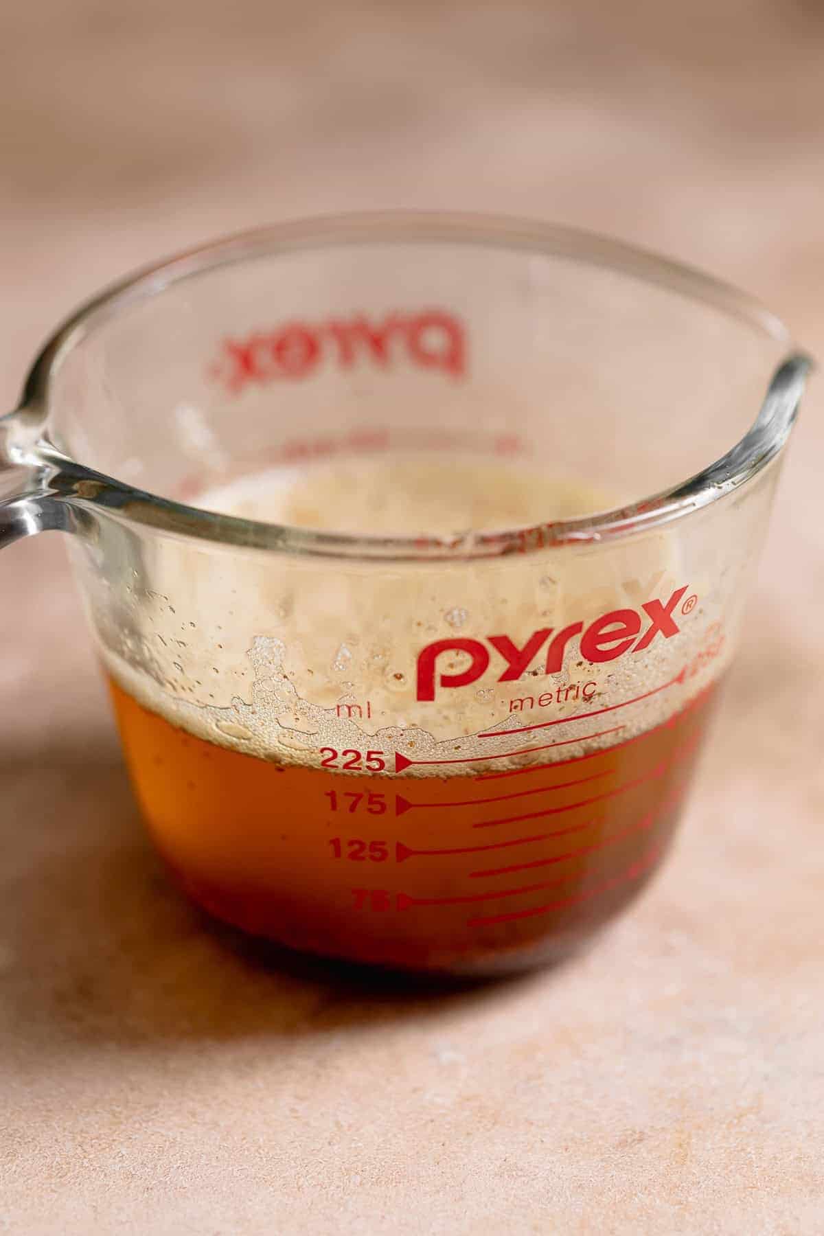 Brown butter with toasted milk solids in a glass measuring cup after cooking until golden brown.