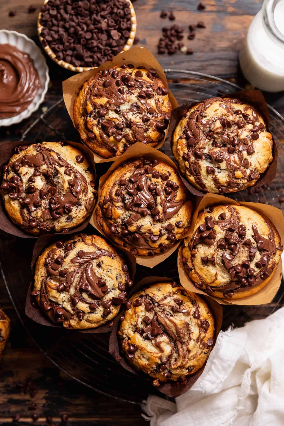 Overhead view of jumbo Nutella muffins topped with Nutella swirls and mini chocolate chips.