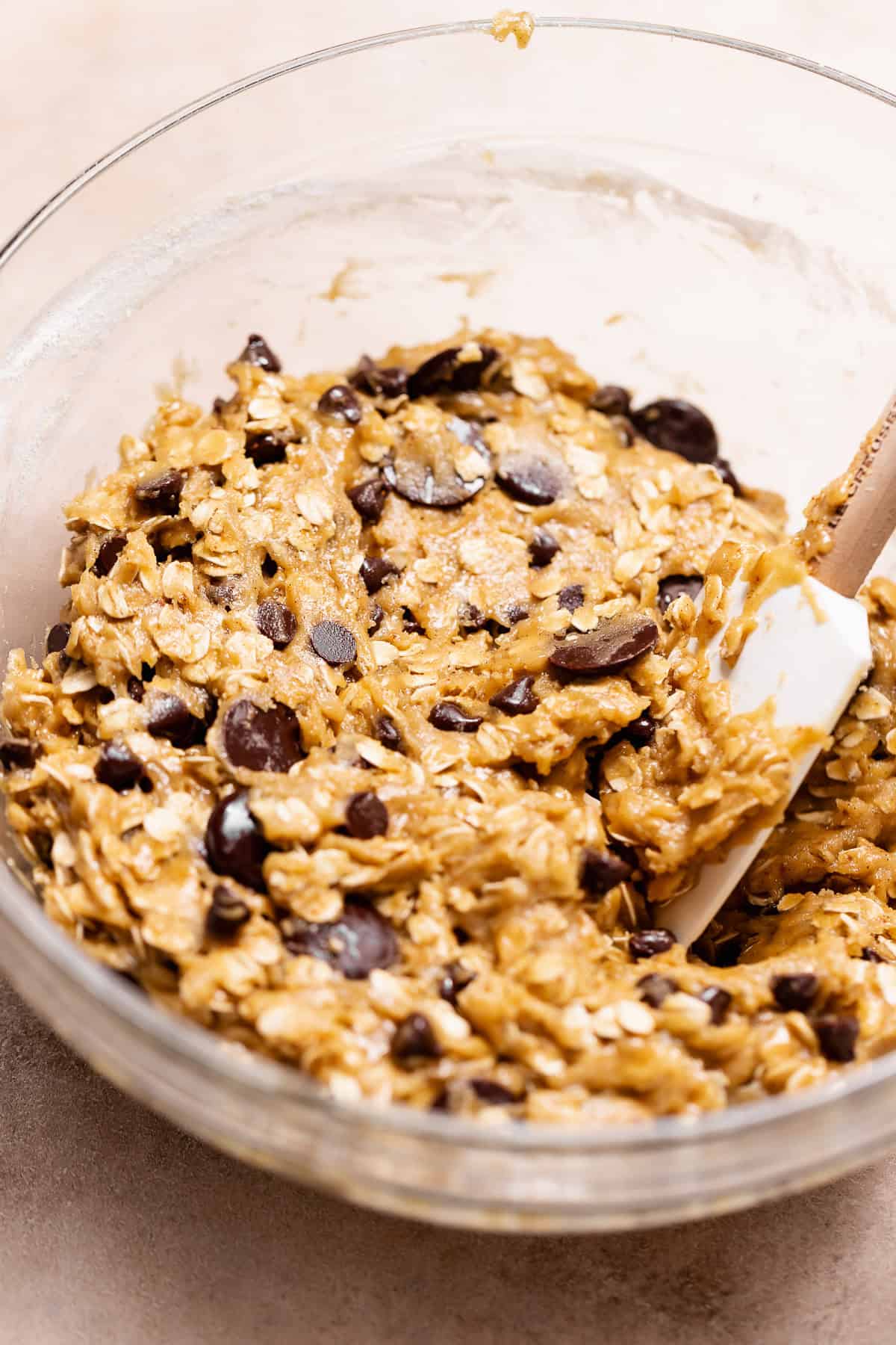 Brown butter oatmeal chocolate chip cookie dough mixed with old-fashioned oats and chocolate chips in a glass bowl.