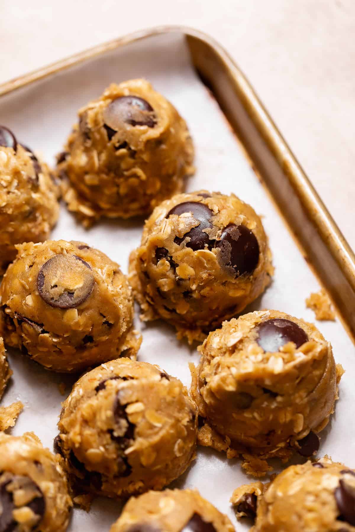 Scooped cookie dough balls on a parchment-lined baking sheet.