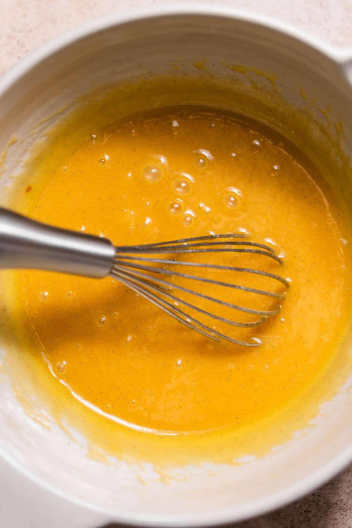 Eggs whisked into the emulsified butter and sugar mixture until smooth and glossy.