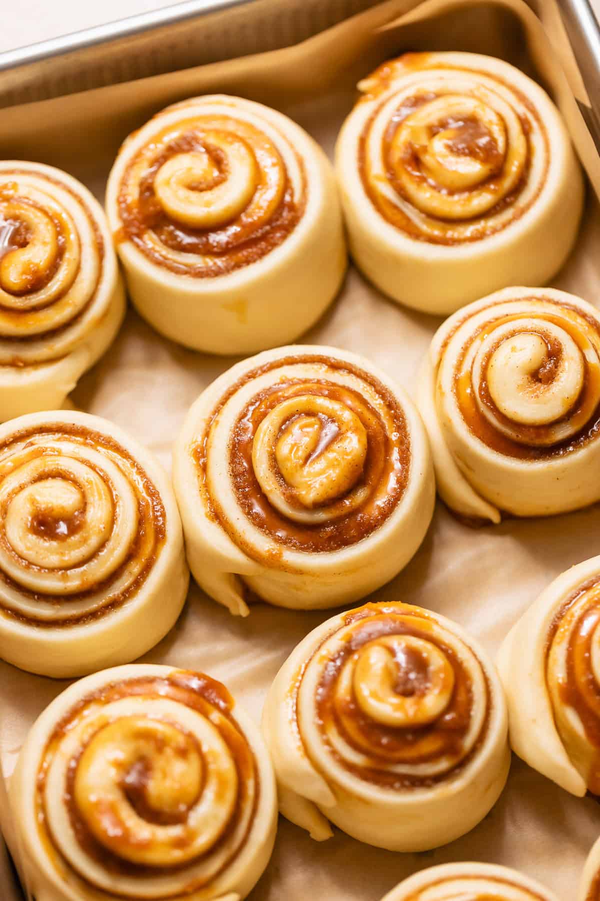 Caramel cinnamon rolls after proofing, showing soft, puffy dough in the baking pan before baking.