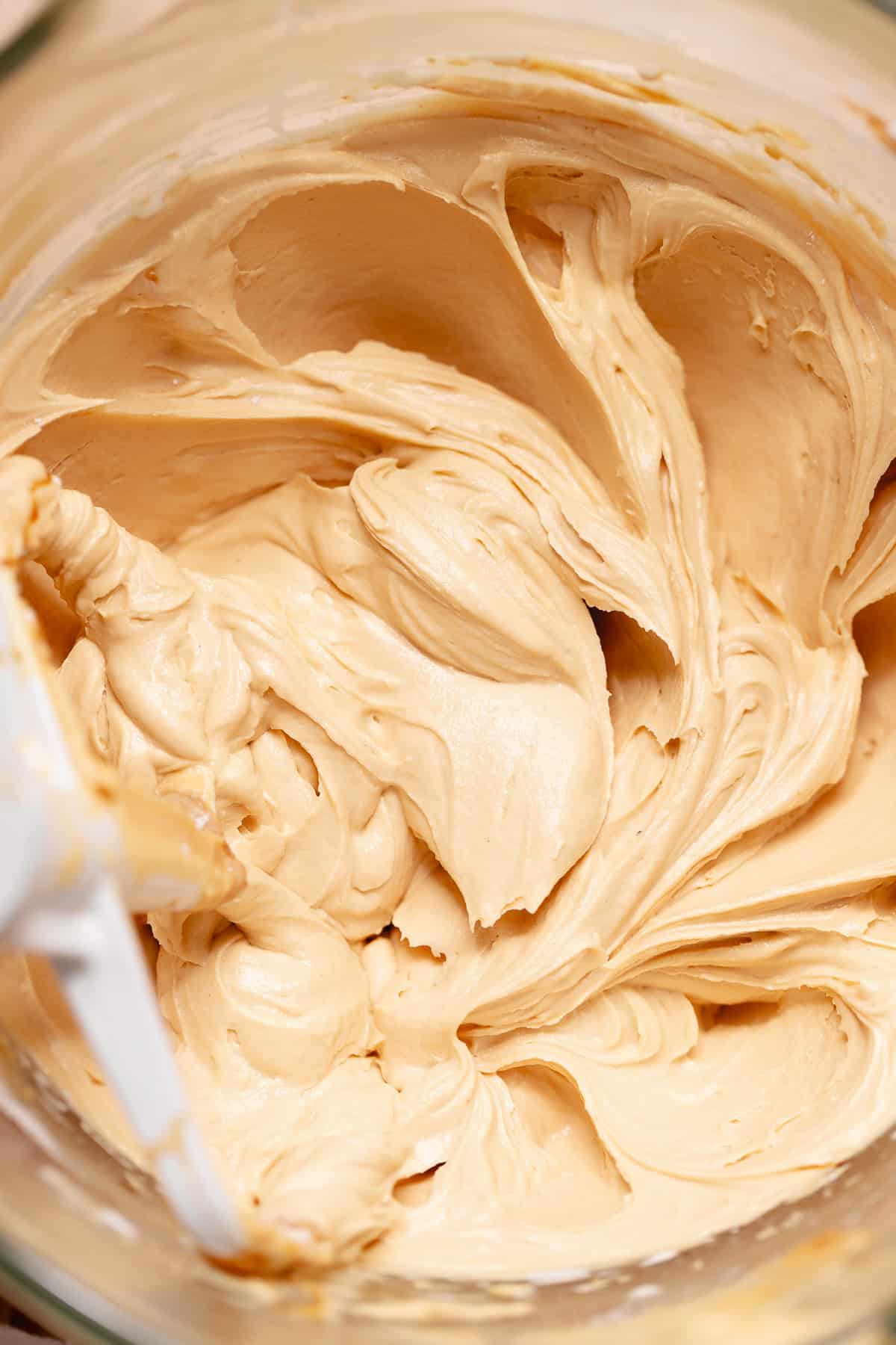 Creamy cookie butter buttercream frosting in a mixing bowl with a spatula.