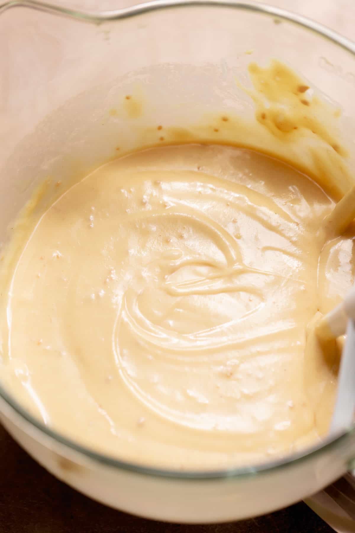 Smooth pale cake batter in a glass mixing bowl.