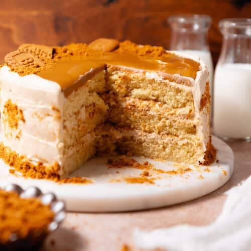 Biscoff layer cake with a large slice removed to show three cake layers and cookie butter frosting inside.