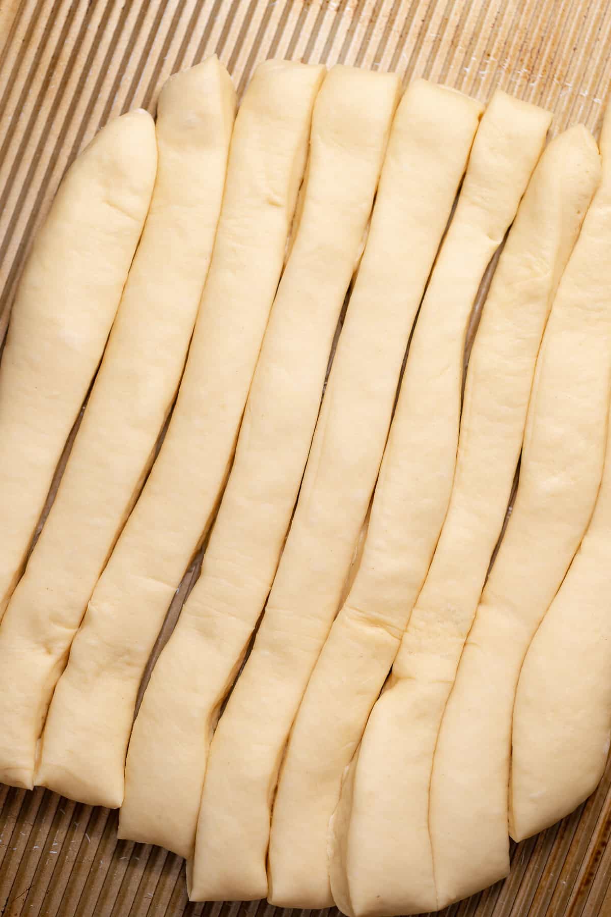 Long strips of yeast donut dough cut into even pieces.