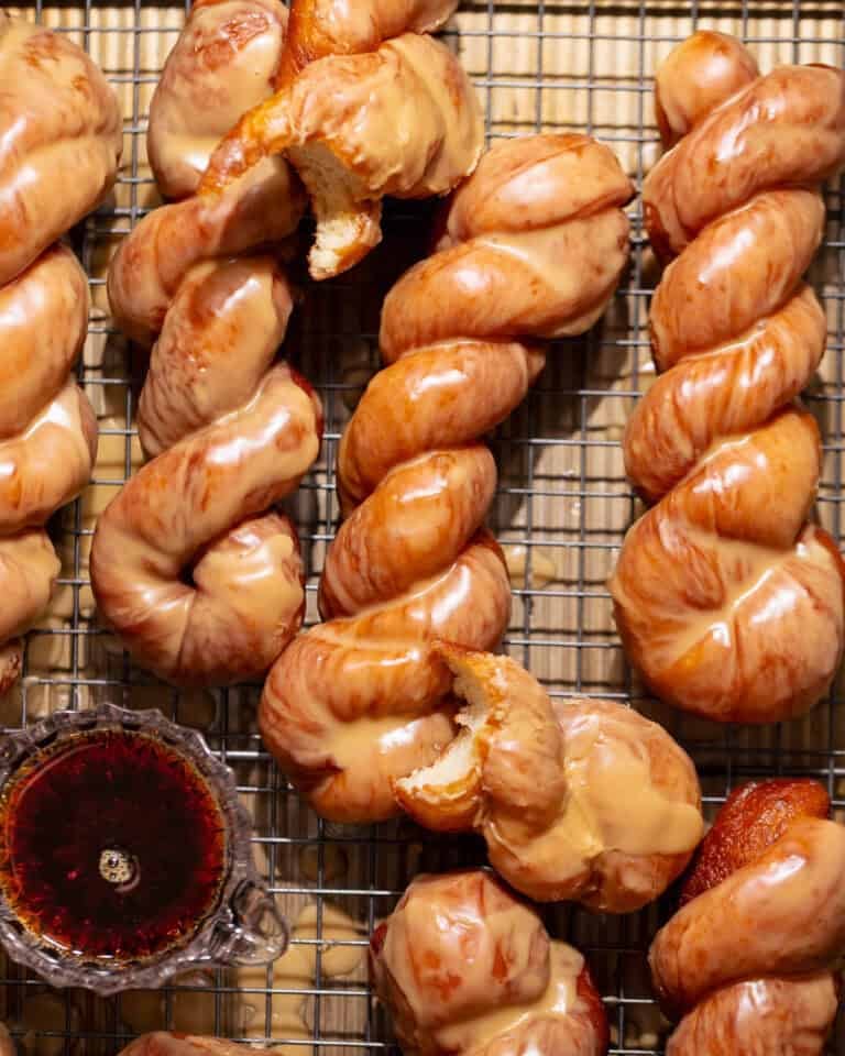 Maple bar donut twists covered in a glossy maple glaze on a cooling rack.