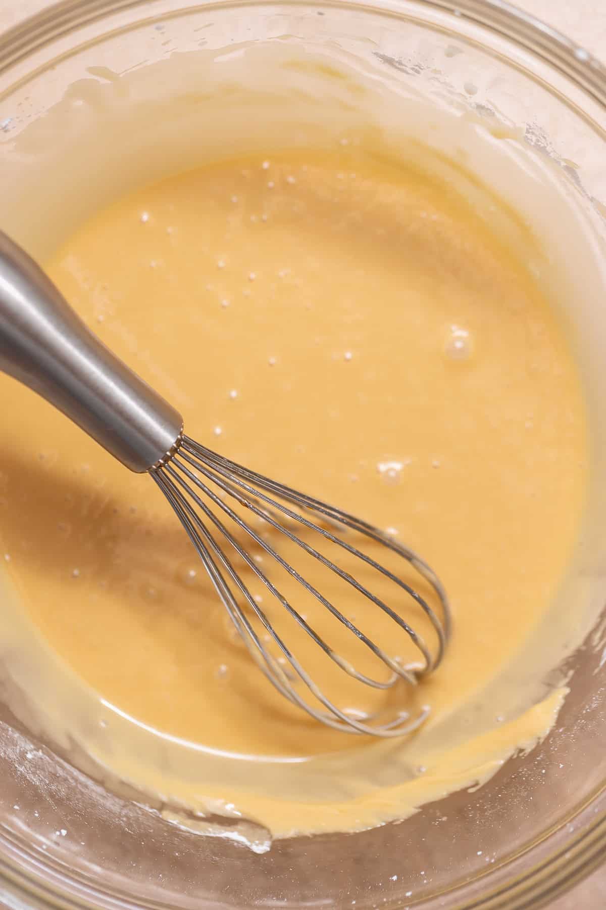 Smooth maple glaze in a glass bowl with a whisk.
