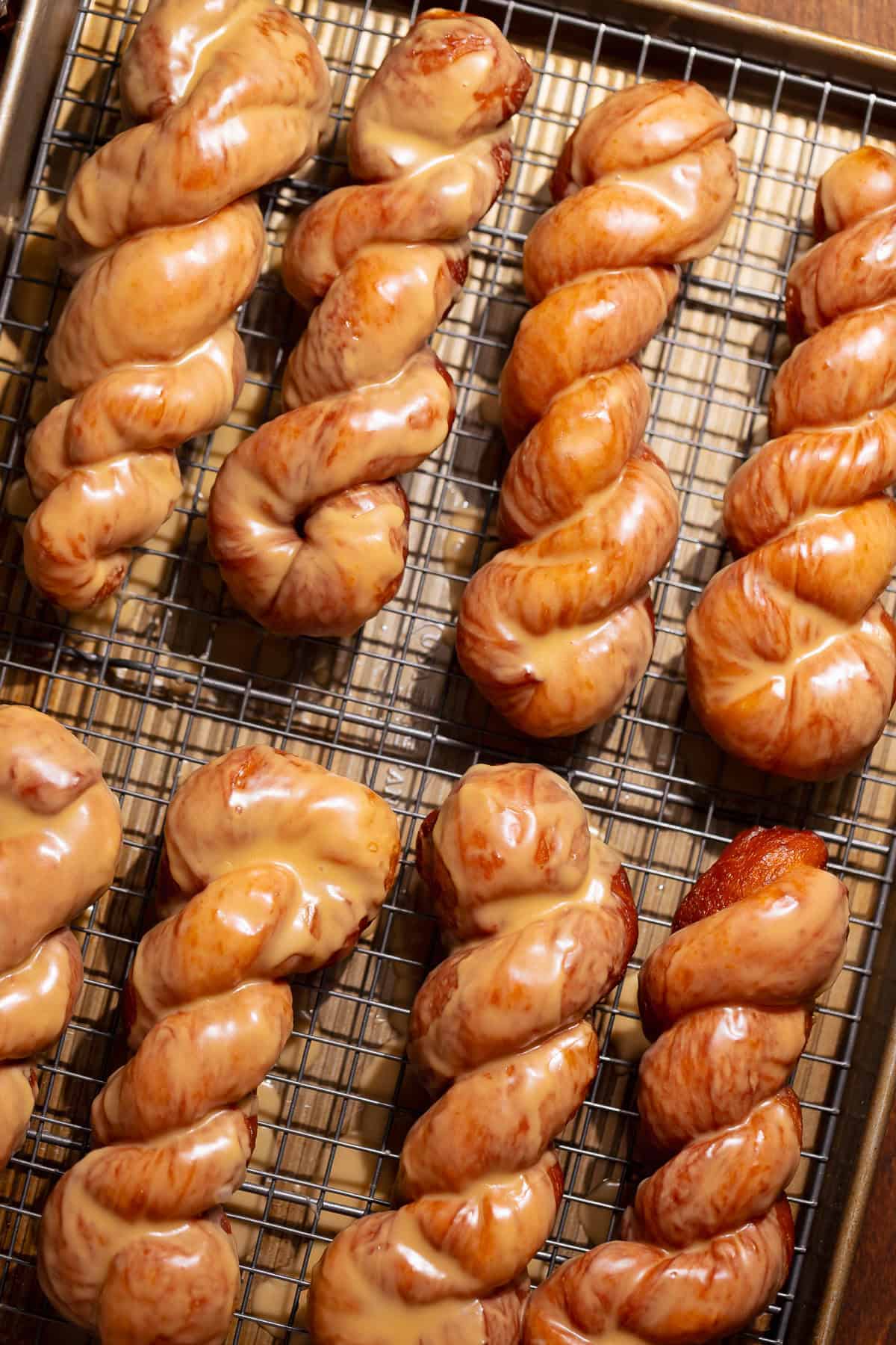 Maple bars arranged on a wire rack after frying and glazing.