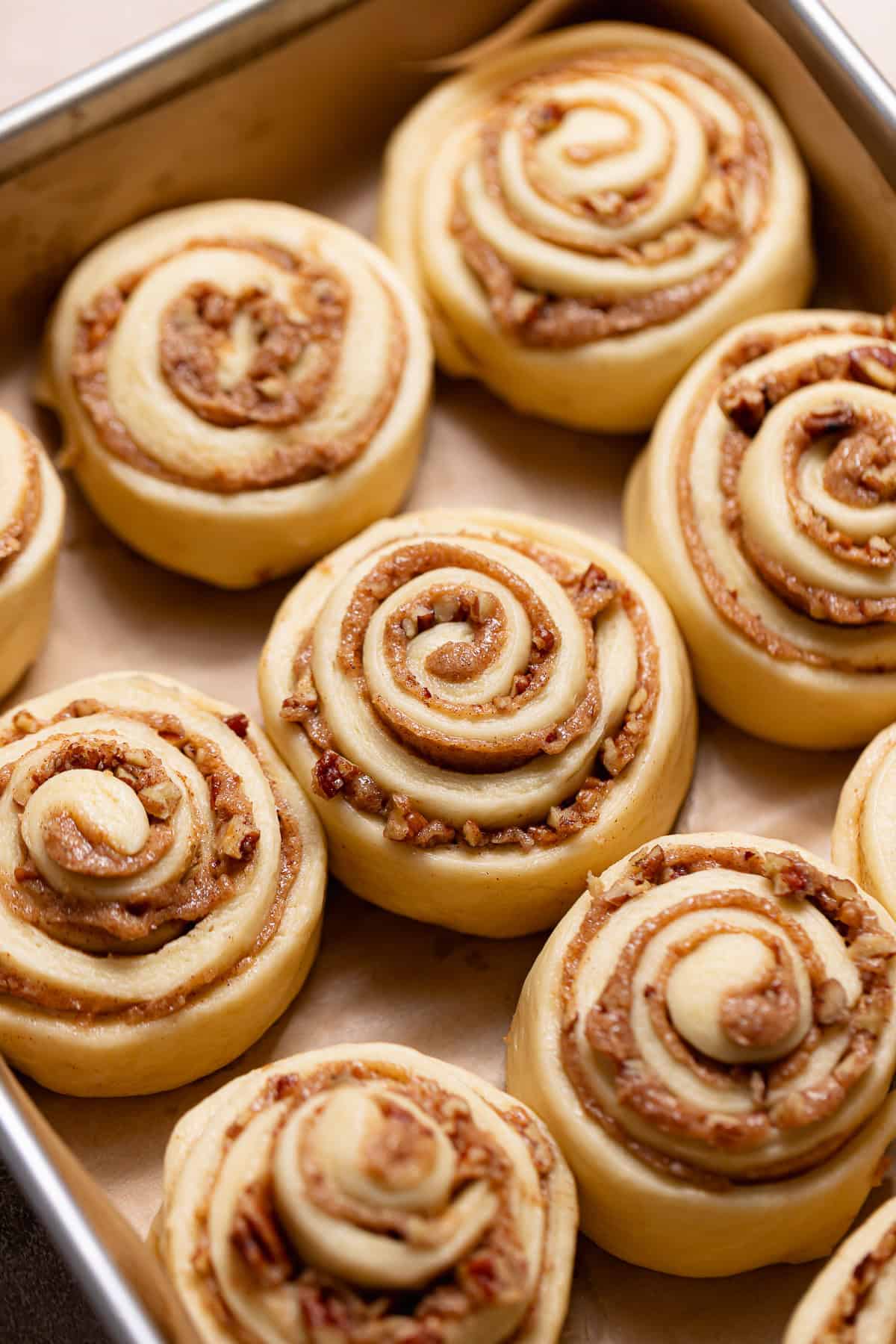 Proofed pecan cinnamon rolls puffed up in a baking pan and ready to bake.