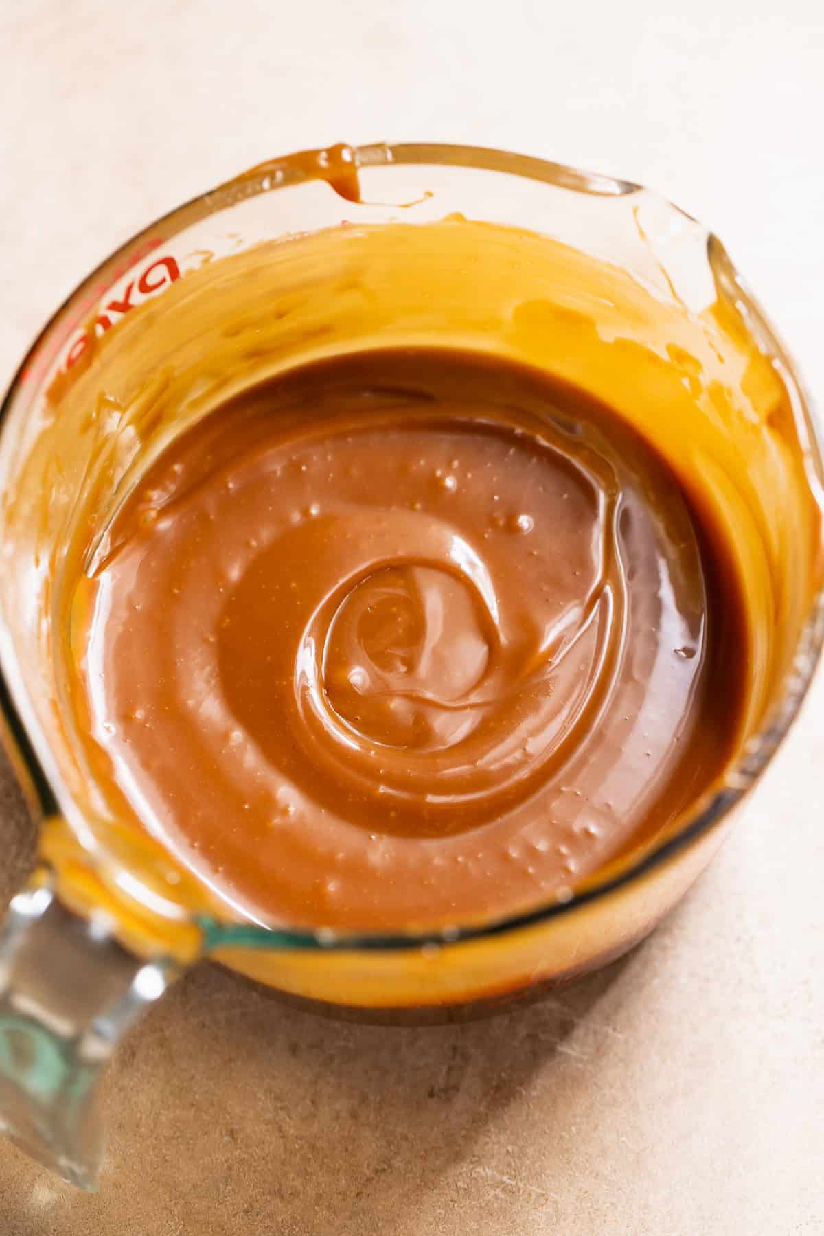 Homemade salted caramel sauce in a glass measuring cup.
