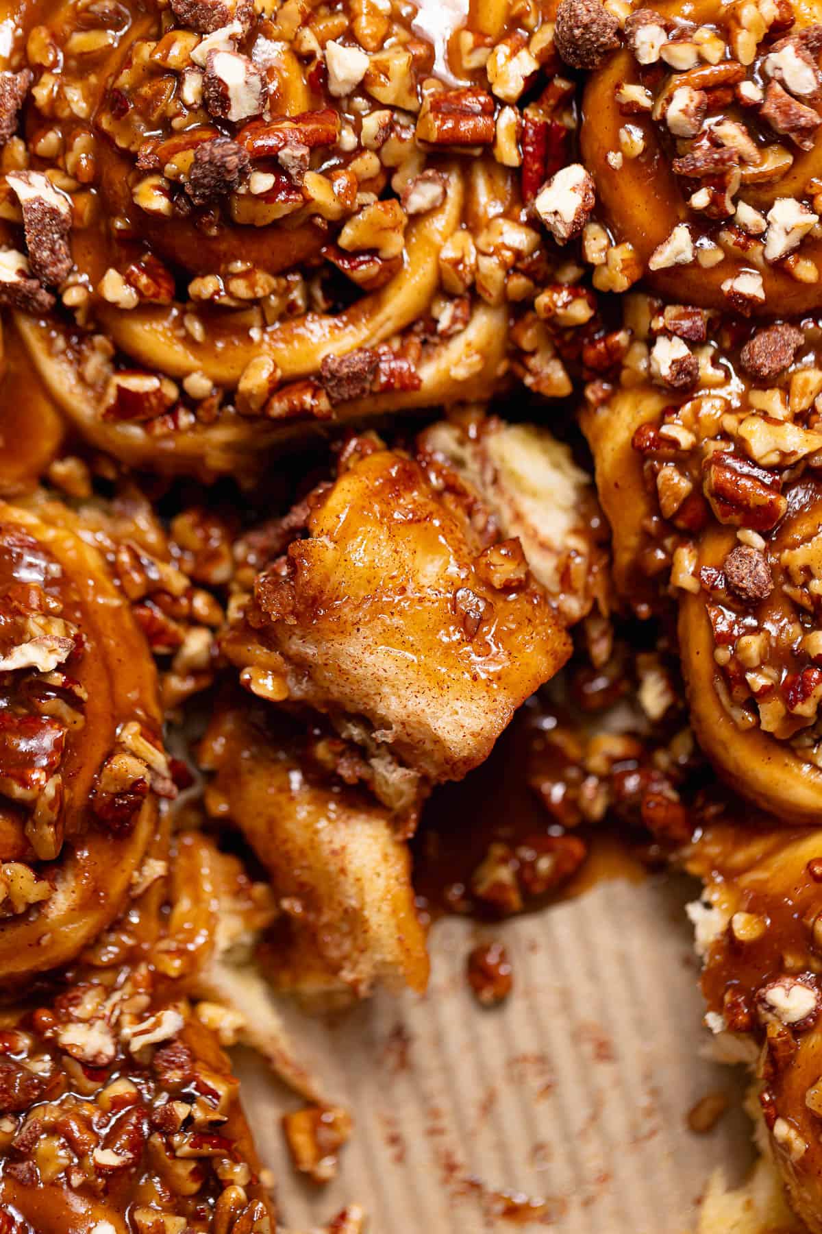 Pecan sticky bun pulled apart to reveal the soft, fluffy center beneath the gooey caramel pecan topping.