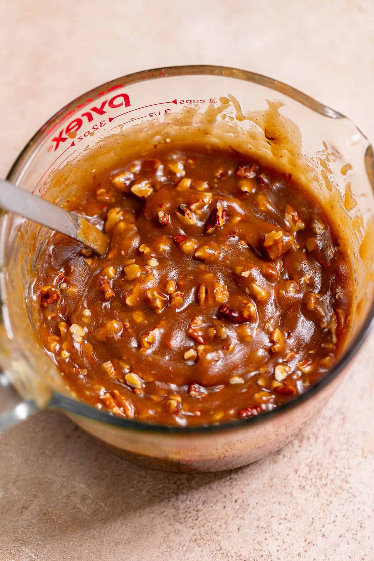 Thick caramel sauce filled with chopped toasted pecans in a glass bowl.