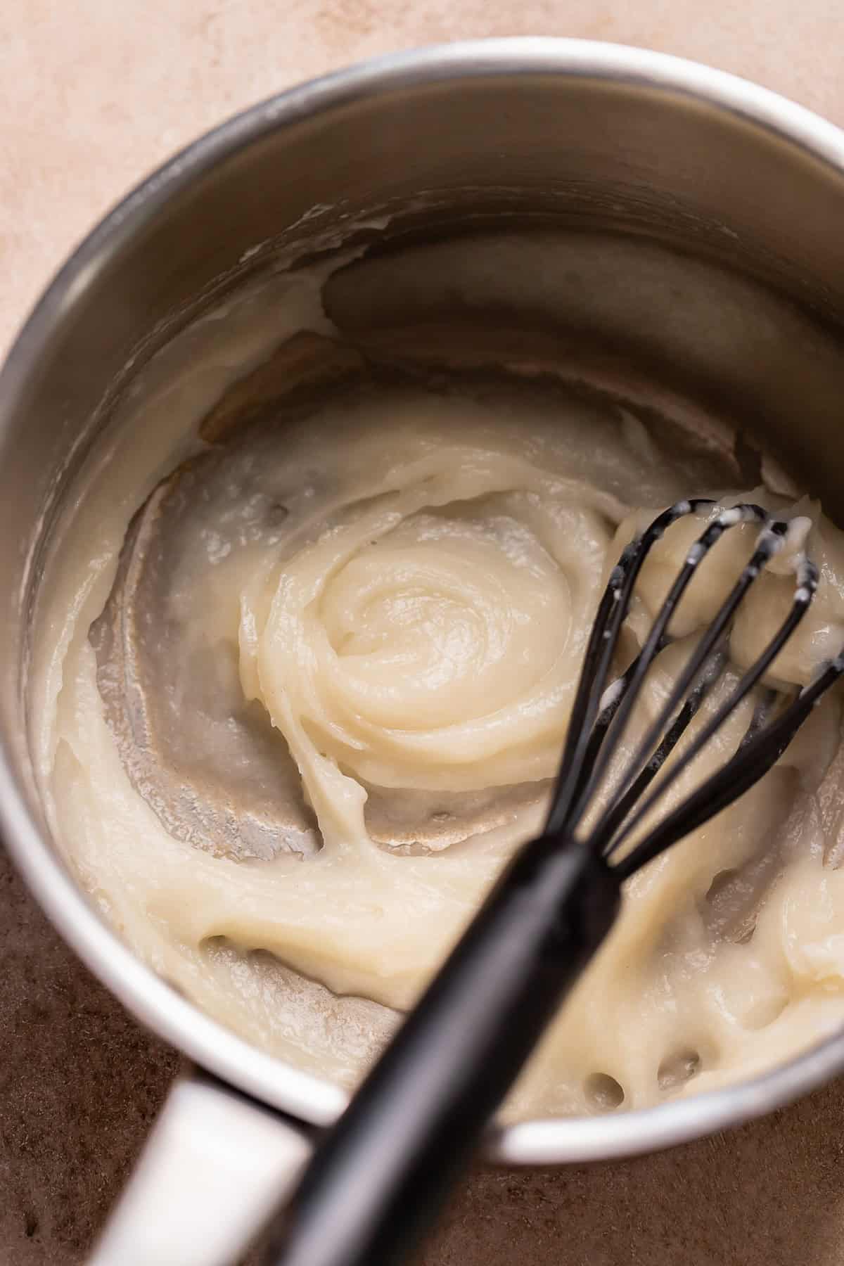Cooked tangzhong paste in a small saucepan with a whisk, showing the thick, smooth consistency.
