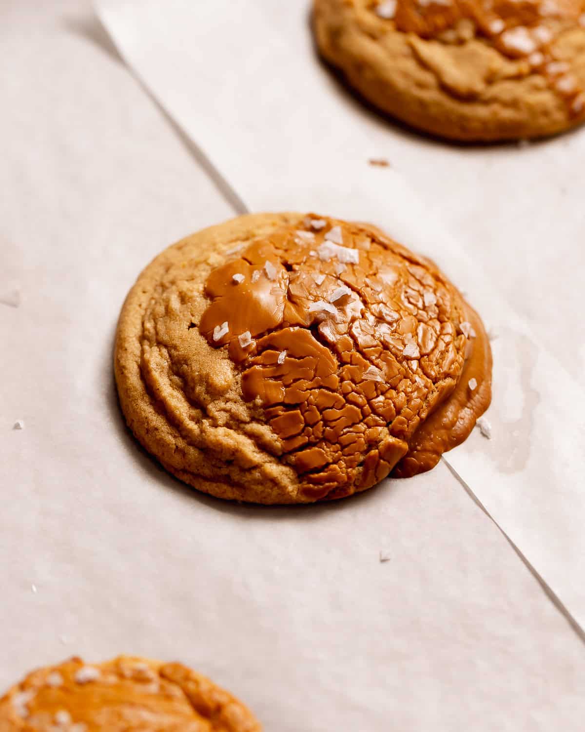 A cookie butter cookie topped with melted Biscoff and sea salt on parchment paper.