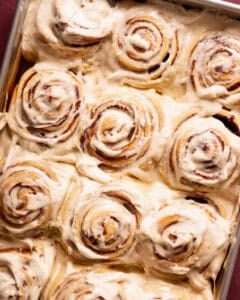 A baking pan filled with frosted cinnamon rolls.