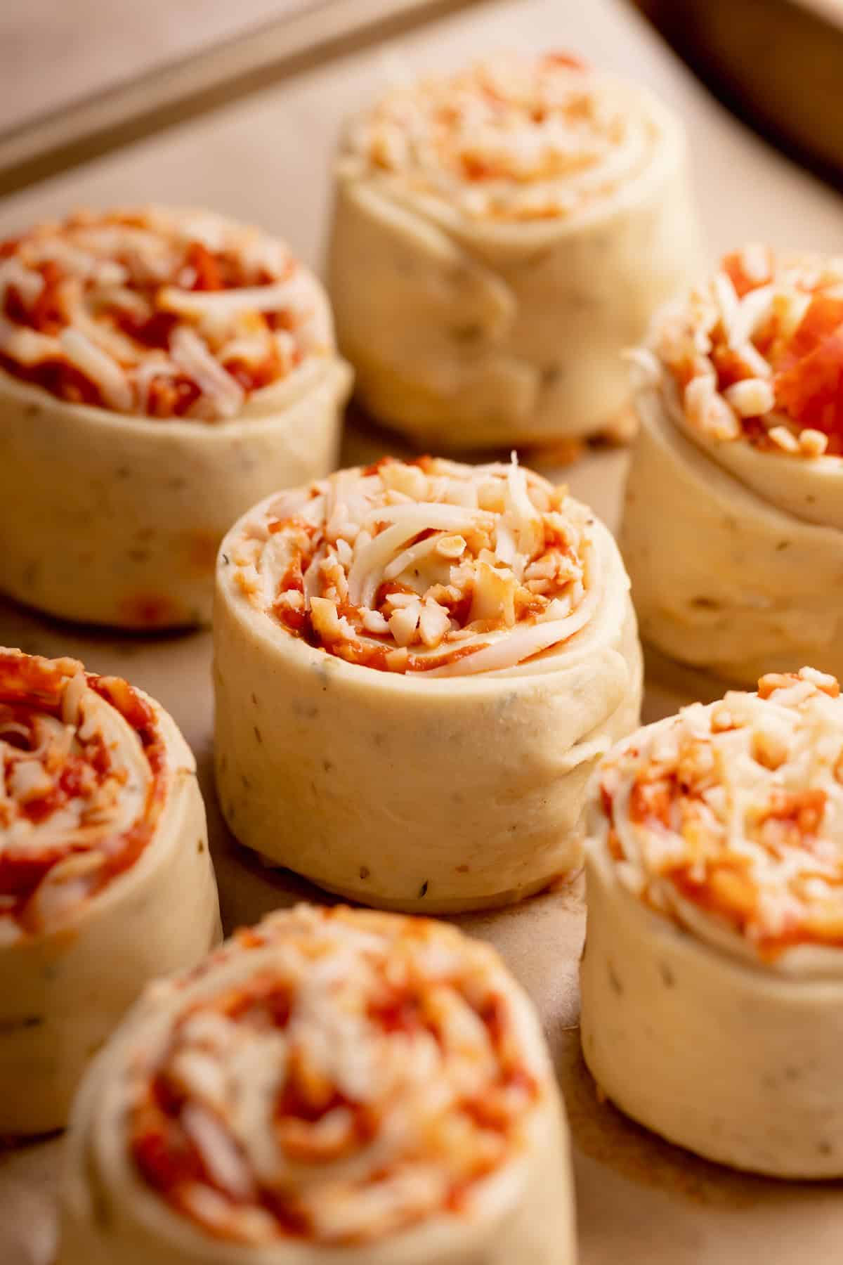 Unbaked pizza pinwheels arranged on a baking sheet.